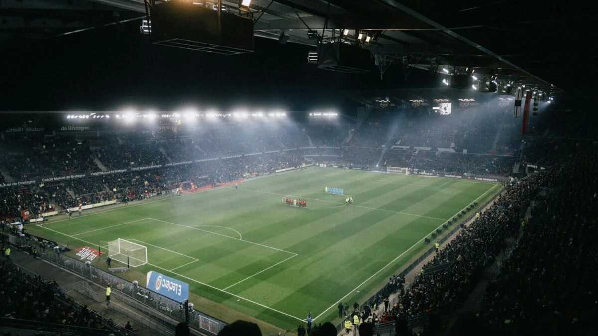 Football stadium filled with supporters under floodlights at night
