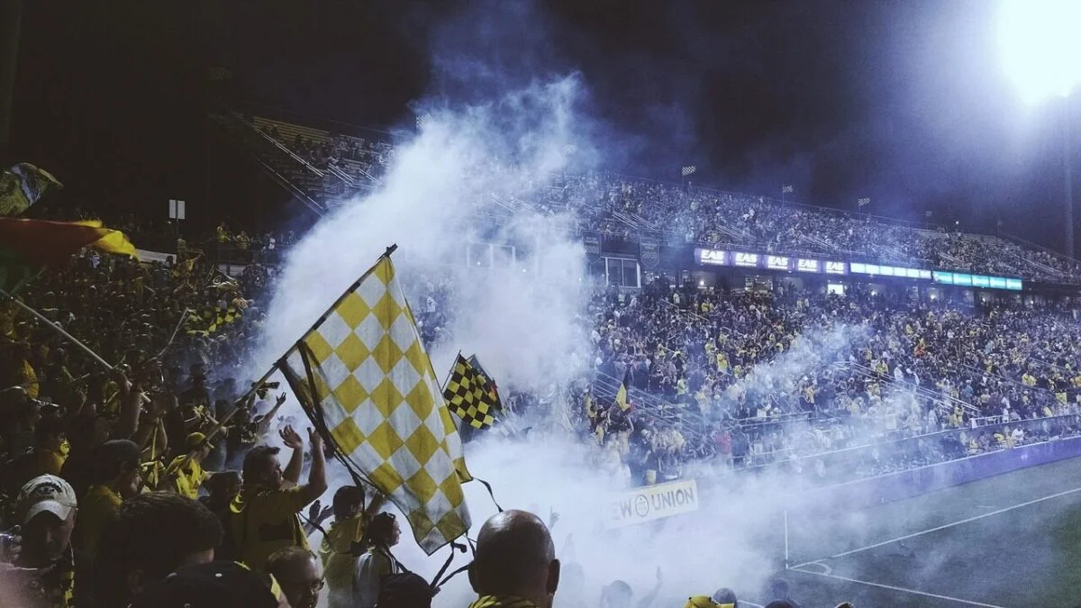 Fans cheering and celebrating in a packed football stadium during a match